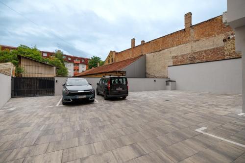 two cars parked in a parking lot next to a building at Apartment Simpatico in Novi Sad