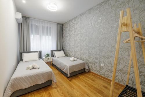 a bedroom with two beds and a wall at Apartment Simpatico in Novi Sad