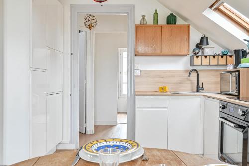 une cuisine avec des placards blancs et une plaque de cuisson sur une table dans l'établissement Le Splendide - Paris - Métro - 4 personnes, aux Lilas