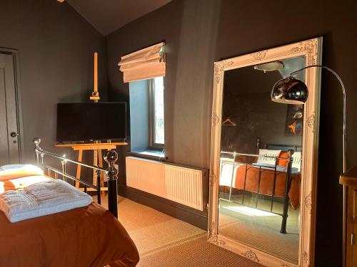 um quarto com um espelho, uma cama e uma televisão em The Balmoral Coach House em Morecambe