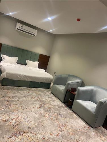 um quarto de hotel com uma cama e duas cadeiras em أضواء الشرق للشقق الفندقية Adwaa Al Sharq Hotel Apartments em Sīdī Ḩamzah