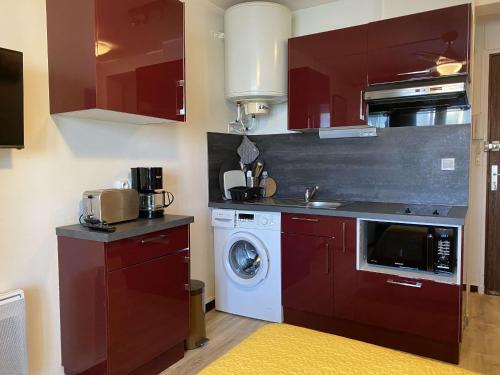 - une cuisine avec des placards rouges et un lave-linge dans l'établissement Joli Studio rénové avec loggia fermée, tout équipé, WIFI, classé 2 étoiles à Balaruc-les-Bains - FR-1-553-161, à Balaruc-les-Bains
