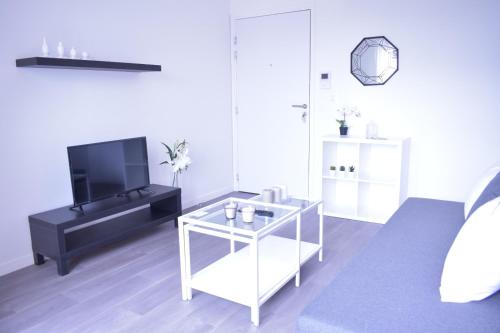 un salon avec une télévision et une table dans l'établissement La Perle de Paris, au Blanc-Mesnil