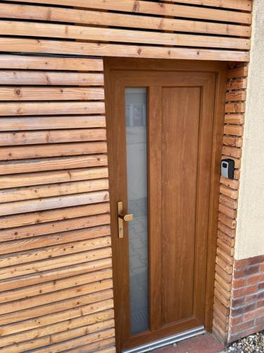 a door to a building with a wooden wall at Apartmán mini Stupava in Stupava