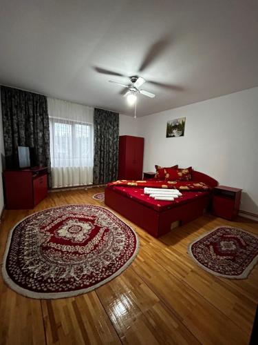 1 dormitorio con 1 cama roja y 2 alfombras en Casa Chindris, en Ocna Şugatag