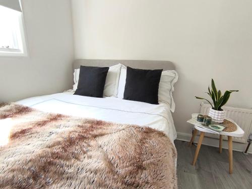 Un dormitorio con una cama y una mesa con una planta en Bright one bedroom apartment in Chiswick, en Londres