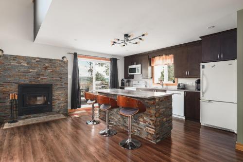 a kitchen with a fireplace and a counter with stools at chalet le Taz in Saint Come