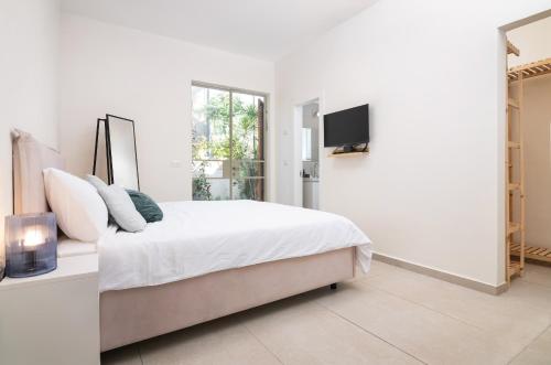 een witte slaapkamer met een bed en een televisie bij Luxury Dolphin House in Tel Aviv
