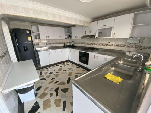 una cocina con armarios blancos y una encimera con elementos amarillos en Casa Mirtha, en Ríohacha