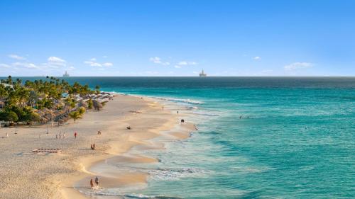 a beach with people on it and the ocean at O Condominium Beachfront Residences, by Bocobay Aruba in Palm-Eagle Beach
