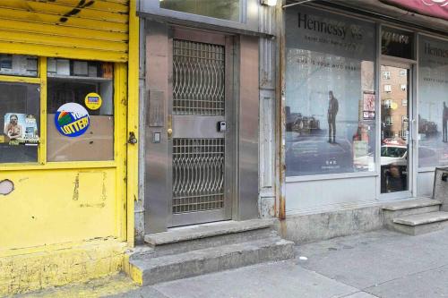 a store with a yellow storefront with a man in the window at Sundrenched East Village Apartment in New York