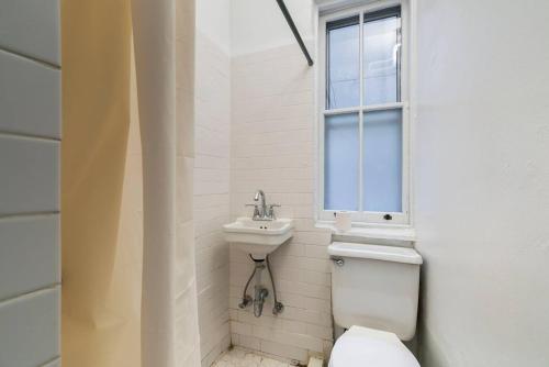 a bathroom with a toilet and a sink and a window at Sundrenched East Village Apartment in New York