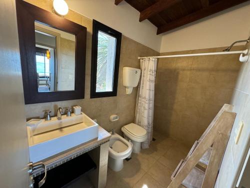 a bathroom with a sink and a toilet and a mirror at Casa espectacular directo sobre el mar in Las Flores