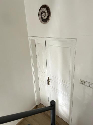 a white door in a room with a clock on the wall at Chambre spacieuse climatisée - SDB privée & Cuisine équipée & Breakfast in Saint-Louis