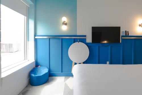 a blue room with a white chair and a tv at The Gallatin in Nashville