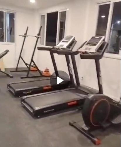 a gym with three treadying machines in a room at Quarto privado in Florianópolis