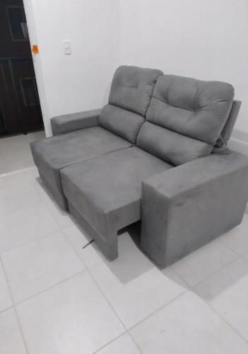 un sofá gris sentado en una sala de estar en Quarto privado en Florianópolis