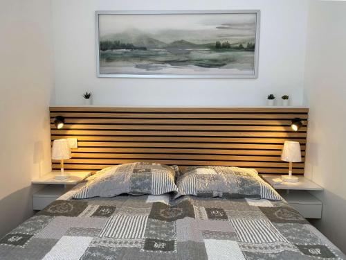 sypialnia z łóżkiem z drewnianym zagłówkiem i 2 lampami w obiekcie T1 rénové avec balcon, clim, wifi, à Balaruc-les-Bains - FR-1-553-220 w mieście Balaruc-les-Bains