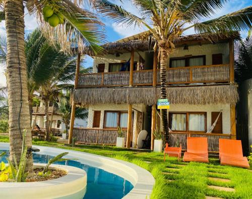 a resort with a swimming pool and palm trees at Pousada Maré Cheia in Itarema