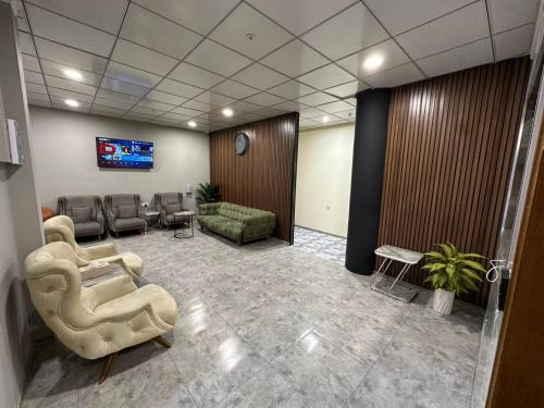 uma sala de espera com sofás e cadeiras e uma televisão em Athena Stars Hotel em Erbil