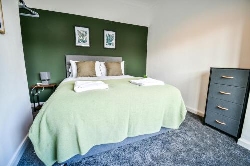 a bedroom with a large bed with a green wall at Keith House Workstays UK 4 Bedrooms in Middlesbrough