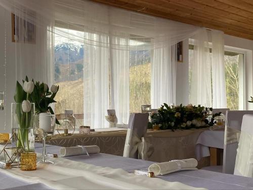 a dining room with white tables and a large window at Chata pod Sokolím in Terchová