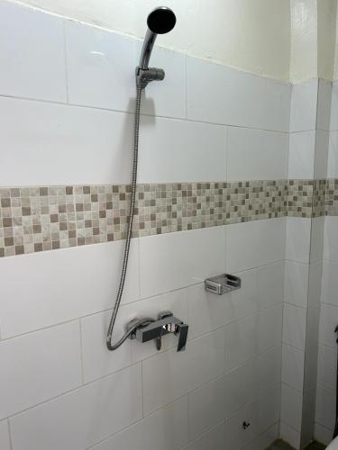 un cabezal de ducha en la pared del baño en Chambre tout confort avec salle de bain intérieure privée - Clim & breakfast en Saint-Louis