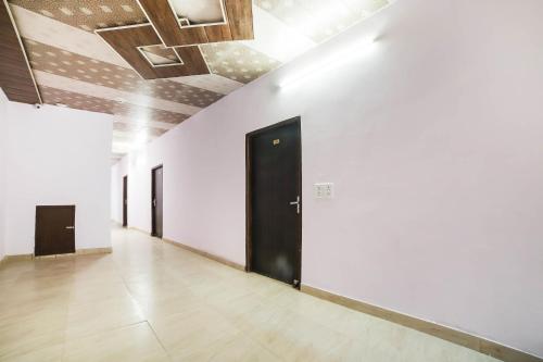 un couloir avec des murs blancs et une porte noire dans l'établissement OYO Kl Khari Inn, à New Delhi