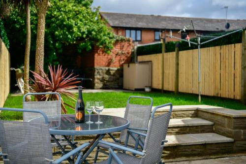 ein Tisch und Stühle mit einer Flasche Wein drauf in der Unterkunft Rare Free Parking in Heart of the City - Highly Rated Townhouse & Garden - Peaceful Area Less Than 5min Walk to Beach, Shops, Bars, Arena, Marina, Parks in Swansea