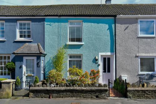 ein blaues Haus mit Blumen davor in der Unterkunft Rare Free Parking in Heart of the City - Highly Rated Townhouse & Garden - Peaceful Area Less Than 5min Walk to Beach, Shops, Bars, Arena, Marina, Parks in Swansea