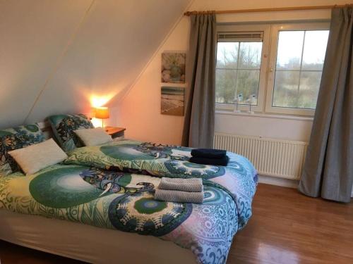 een slaapkamer met een groot bed en een kleurrijke deken bij Beachvilla Grachtenkom in Makkum