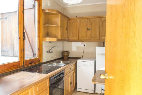uma cozinha com armários de madeira, um lavatório e um frigorífico em Apartamentos Grist em Eriste