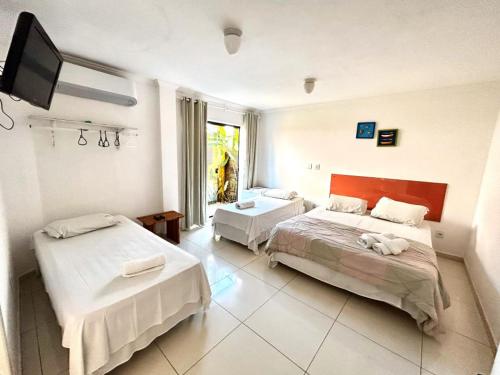 a bedroom with two beds and a flat screen tv at Pousada Maravilha de Paraty in Paraty