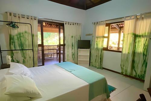 a bedroom with a white bed and a television at Flat Oxóssi em condomínio beira-mar com varandão cozinha e piscina in Marau