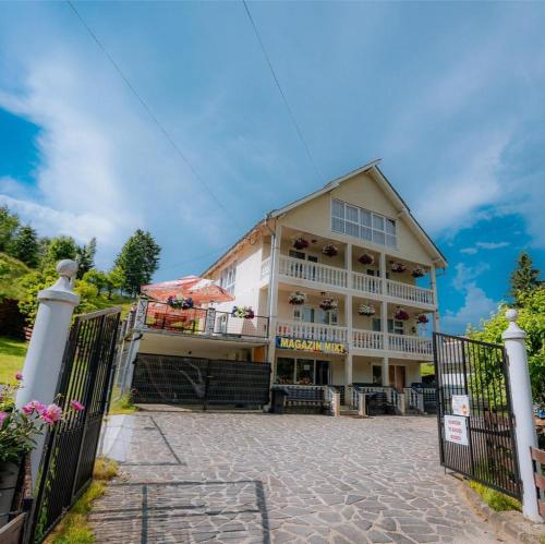 a large building with a fence in front of it at Casa Munții Rodnei in Borşa