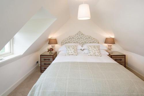 1 dormitorio con 1 cama blanca grande y 2 mesitas de noche en Garden Cottage, Teviot Bank, en Denholm