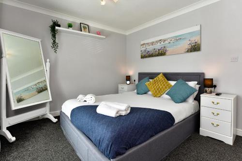 a bedroom with a bed with a blue blanket and a mirror at Rare Free Parking in Heart of the City - Highly Rated Townhouse & Garden - Peaceful Area Less Than 5min Walk to Beach, Shops, Bars, Arena, Marina, Parks in Swansea