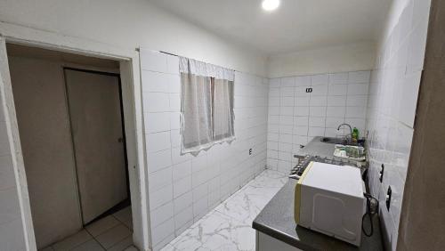 Hostal Turismo Quintamar 1 في فينيا ديل مار: حمام من البلاط الأبيض مع حوض وميكروويف