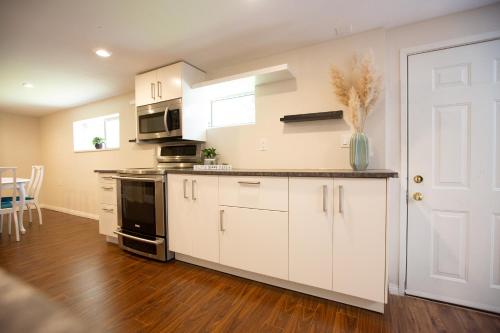 cocina con armarios blancos y puerta blanca en Private Garden-Level Suite, en West Vancouver