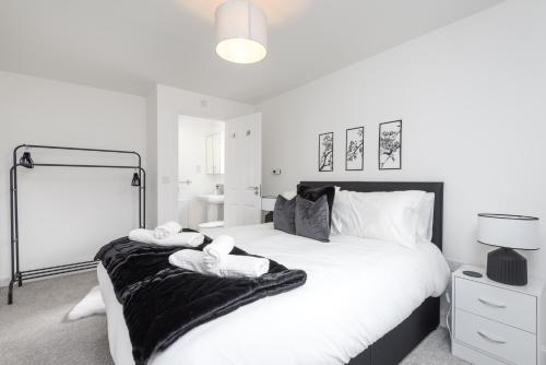 a white bedroom with a large bed with towels on it at Spacious Luxury House In Canterbury with Free Parking, Sleeps 7 in Canterbury