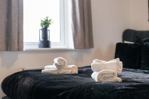 a pile of towels sitting on top of a bed at Spacious Luxury House In Canterbury with Free Parking EV, Sleeps 7 in Sturry