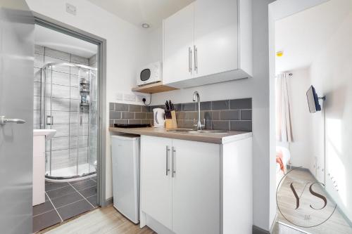 a white kitchen with a sink and a shower at Bright Longton Studio B Near Alton Towers with Netflix and Free Wi-Fi in Stoke on Trent