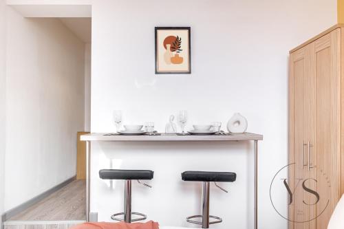 a small kitchen with a bar with two stools at Bright Longton Studio B Near Alton Towers with Netflix and Free Wi-Fi in Stoke on Trent