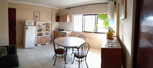 a kitchen with a table and chairs and a refrigerator at Departamento Simple in Cochabamba