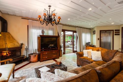 a living room with a couch and a television at Pousada Villa D'Biagy in Campos do Jordão