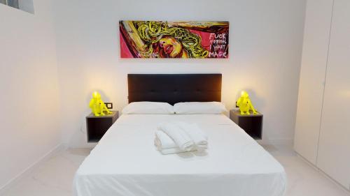 1 dormitorio con 1 cama blanca y una pintura en la pared en Agd Living 1, en Algarrobo Costa