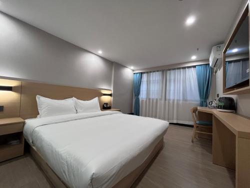 um quarto com uma grande cama branca e uma secretária em Pod Hotel - Guangzhou Luoxi Subway Station Canton Tower em Guangzhou