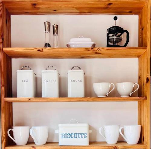 a wooden shelf filled with white cups and utensils at The Hideout in Linton