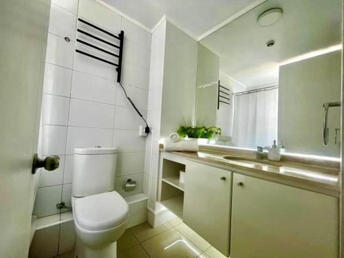 a white bathroom with a toilet and a sink at Departamento galáctico con vista al desierto in Calama