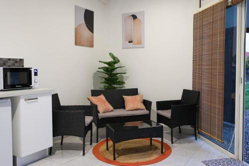 a living room with a couch and chairs and a table at Grand studio Bis à Matoury in Matoury
